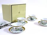 four cups and saucers sitting in front of a box