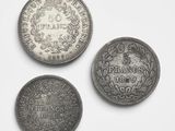 trois types différents de pièces d'argent sur une surface blanche