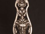 a close up of a silver spoon with a face on it