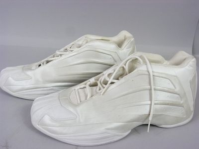 une paire de baskets blanches avec des lacets blancs, posée sur une surface blanche