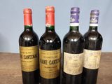 four bottles of wine are lined up on a wooden table