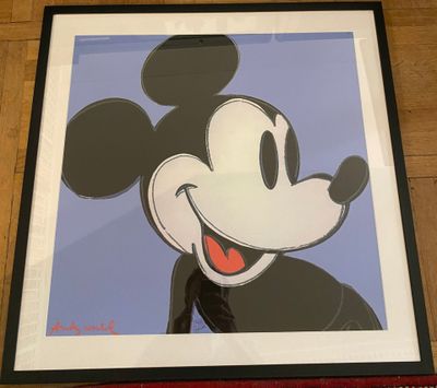 a framed mickey mouse painting on a wooden floor with a red frame