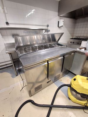 un homme qui nettoie une cuisine avec un aspirateur