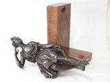 statue of a woman laying on a wooden block on a white background
