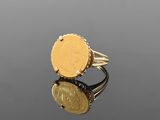 a close up of a gold ring with a coin on it