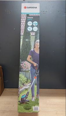 Une femme se tient devant un carton contenant une tondeuse à gazon.