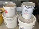 three buckets of paint are stacked on top of each other in a garage