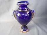 a purple vase sitting on a stand on a white background