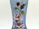 un vase bleu sur lequel sont peintes des fleurs sur fond blanc