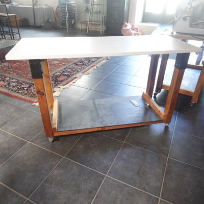 une table blanche avec un piètement en bois posée sur un sol carrelé