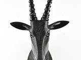 une tête d'antilope noire fixée sur un mur blanc