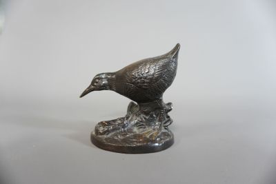 statue représentant un oiseau posé sur un rocher, sur un fond blanc