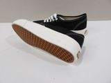 black and white vans style sneakers with gum soles on a white surface