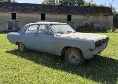 une vieille voiture garée devant une grange