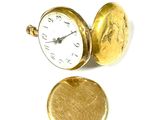 une montre de poche en or posée à côté d'une pièce d'or