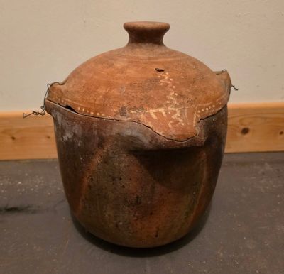 un grand pot marron posé par terre près d'un mur
