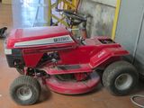 a red lawn mower sitting on the floor in a garage