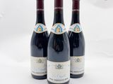 trois bouteilles de vin rouge posées l'une à côté de l'autre sur une surface blanche