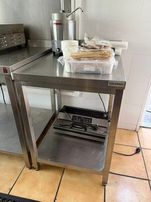 une cuisine avec une table en inox et un grille-pain posé sur le plan de travail