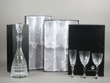 trois verres à vin, une carafe et une carafe dans une boîte