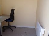 a desk with a chair and a radiator in an empty room