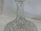 une carafe en verre transparent posée sur une nappe blanche, sur fond blanc