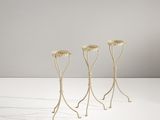 trois supports métalliques pour plantes posés sur une surface blanche, avec un fond blanc