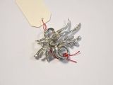 a silver brooch with a red string attached to it