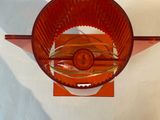 a red glass bowl on a stand on a white surface