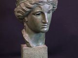 sculpture of a woman ' s head on a block with a black background