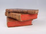three old books stacked on top of each other on a white surface
