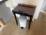 a white trash can sitting next to a wooden table