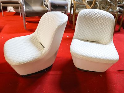 pair of white chairs on a red carpeted floor in a room