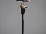 une lampe noire surmontée d'un oiseau, à côté d'un abat-jour