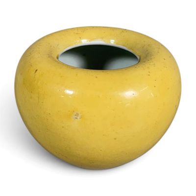 a yellow vase that is sitting on a white surface