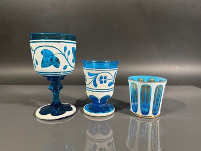 three blue and white glass goblets sitting on top of a table