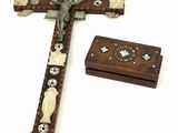 une croix en bois ornée de crânes et de croix, posée à côté d'une boîte en bois