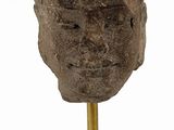 an image of a stone head on a stand on a white surface