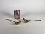 deux cuillères et une tasse posées sur une table, sur fond blanc