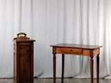 une petite table sur laquelle se trouve une horloge, à côté d'un petit meuble