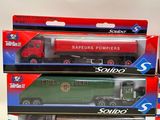 three boxed toy trucks are sitting in a row on a white surface