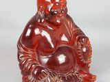 une image représentant une petite statuette de Bouddha rouge posée sur une surface blanche