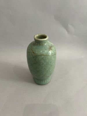 a small green vase sitting on a white surface