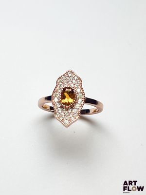 un gros plan d'une bague sertie d'un saphir jaune entouré de diamants blancs