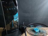 une table sur laquelle sont posés une raquette de tennis et un ventilateur
