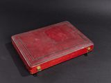 an old red book sitting on top of a black table