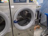 Plusieurs machines à laver sont alignées les unes à côté des autres dans une buanderie