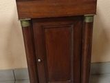 a small wooden cabinet with a black top on a tiled floor