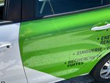 a green and white car that is parked on the side of the road