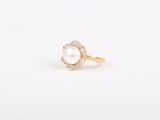 une bague en perle blanche et diamants posée sur une surface blanche